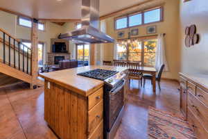 Kitchen with gas stove, island range hood, a fireplace, light countertops, and a kitchen island
