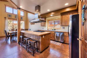 Kitchen with tile counters, a kitchen bar, finished concrete flooring, appliances with stainless steel finishes, and recessed lighting