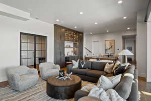 Living room featuring light wood-style flooring, recessed lighting, bar with sink, and wine cooler