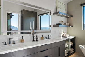 Bathroom with double vanity, a soaking tub, tile walls, and tasteful backsplash