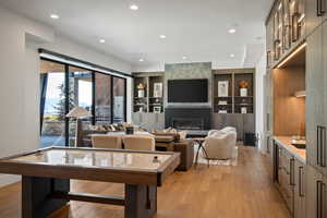 Living room with recessed lighting, a fireplace, light wood-type flooring, and built in shelves