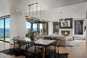 Dining room with light wood-type flooring, recessed lighting, a stone fireplace, and a water and mountain view