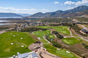 Aerial view of property and surrounding area with a golf course and a water and mountain view