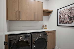Washroom featuring cabinet space and washer and clothes dryer