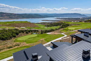 View of community with view of golf course, a water and mountain view, and an area to practice putting