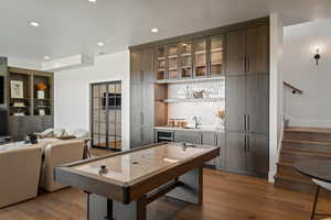 Playroom with dark wood-style floors, recessed lighting, bar with sink, wine cooler, and built in shelves