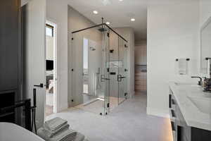 Bathroom with double vanity, a shower stall, connected bathroom, recessed lighting, and a soaking tub