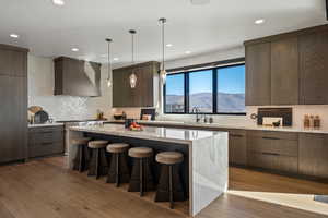 Kitchen featuring modern cabinets, light stone countertops, pendant lighting, and recessed lighting