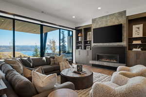 Living room with a fireplace, wood finished floors, recessed lighting, and built in shelves