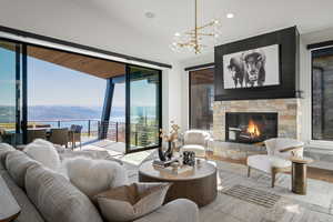 Living area featuring a water and mountain view, wood finished floors, a stone fireplace, recessed lighting, and vaulted ceiling