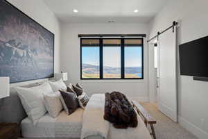 Carpeted bedroom with a barn door and recessed lighting