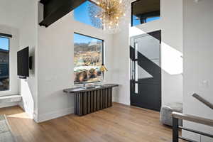 Entrance foyer featuring light wood-type flooring, a chandelier, plenty of natural light, and a towering ceiling