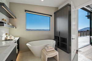 Bathroom with a soaking tub, tile walls, vanity, and a mountain view