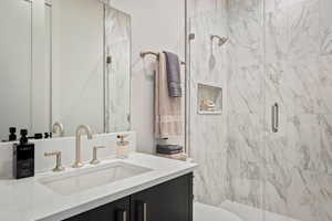 Bathroom with vanity and a marble finish shower