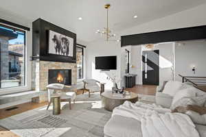 Living area with wood finished floors, recessed lighting, lofted ceiling, a fireplace, and a chandelier
