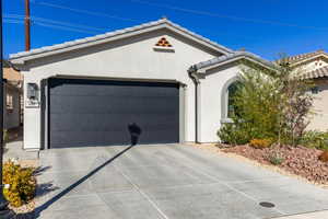 View of front facade with a garage, driveway, stucco siding, and a tile roof