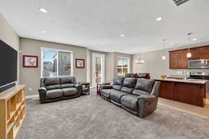 Living area featuring light colored carpet, a textured ceiling, recessed lighting, and a chandelier