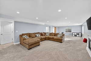 Living room with a glass covered fireplace, light carpet, and recessed lighting