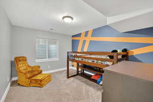 Bedroom featuring light carpet, a textured ceiling, and an accent wall