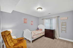Carpeted bedroom featuring a textured ceiling and baseboards