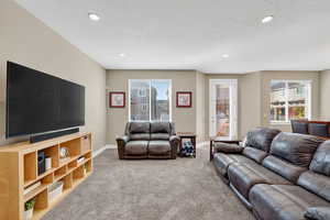 Living room featuring carpet flooring, healthy amount of natural light, a textured ceiling, and recessed lighting