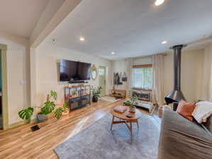 Living area featuring a wood stove, recessed lighting, and wood finished floors