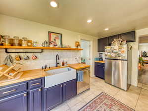 Kitchen featuring open shelves, stainless steel appliances, backsplash, recessed lighting, and wooden counters