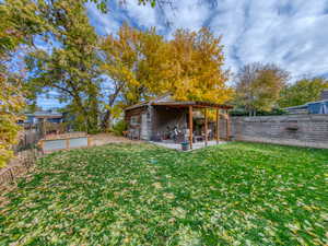 Fenced backyard featuring a patio area, garden & Storage Garage.