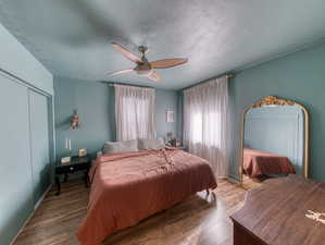 Bedroom featuring a closet, wood finished floors, ceiling fan, and a textured ceiling