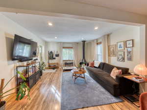 Living room featuring light wood-style floors, a wood stove, and recessed lighting