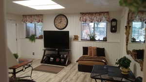 Sitting room featuring wooden walls, wood finished floors, and healthy amount of natural light