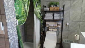 Full bathroom with a shower stall, vanity, and tile walls