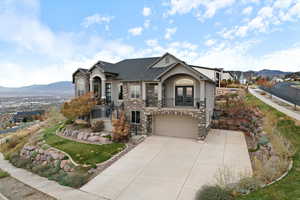 View of front of property with stucco siding, a mountain view, french doors, a balcony, and a garage