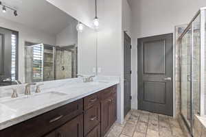 Full bathroom with double vanity, a stall shower, and lofted ceiling
