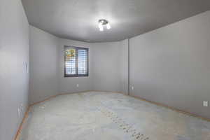 Empty room featuring a textured ceiling and baseboards