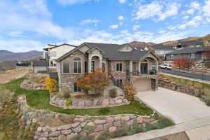 View of front facade featuring a mountain view, concrete driveway, a garage, stucco siding, and stairway