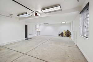 Garage featuring a garage door opener and baseboards