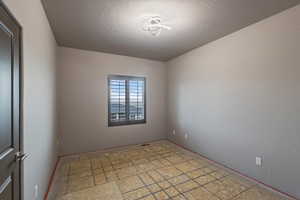 Spare room featuring a textured ceiling and baseboards