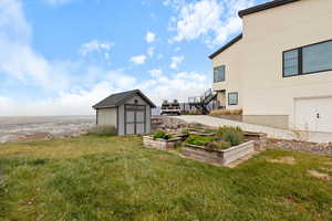 View of green lawn featuring a vegetable garden, a shed, and stairway