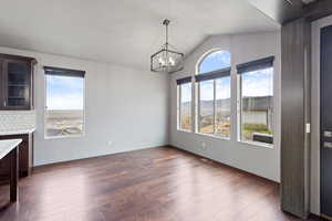 Unfurnished dining area with dark wood finished floors, a mountain view, vaulted ceiling, and a chandelier