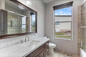 Full bathroom with healthy amount of natural light, vanity, and stone tile flooring