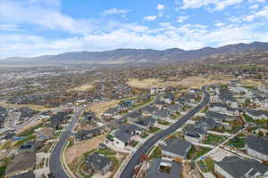 Aerial view of property and surrounding area featuring nearby suburban area and a mountainous background