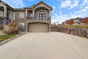 View of front facade with stucco siding, stone siding, concrete driveway, and a balcony