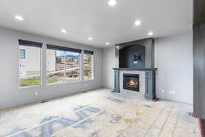 Unfurnished living room with a tiled fireplace and recessed lighting