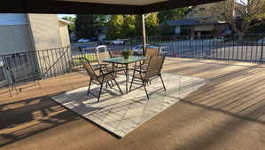 Spacious covered patio with brown outdoor carpeting and decorative black metal railing