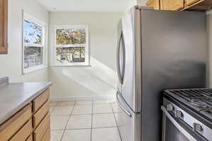 Kitchen featuring light tile patterned floors, brown cabinets, and stainless steel range with gas stovetop