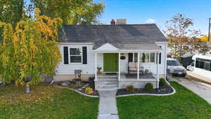 View of front of home featuring a shingled roof, a chimney, and a front lawn