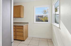Bar area with light tile patterned floors, light countertops, and brown cabinetry