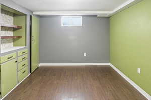 Below grade area with dark wood-style flooring and baseboards