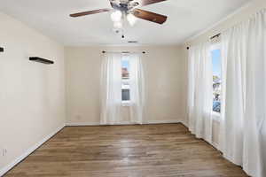 Unfurnished room featuring light wood-style floors, healthy amount of natural light, and a ceiling fan